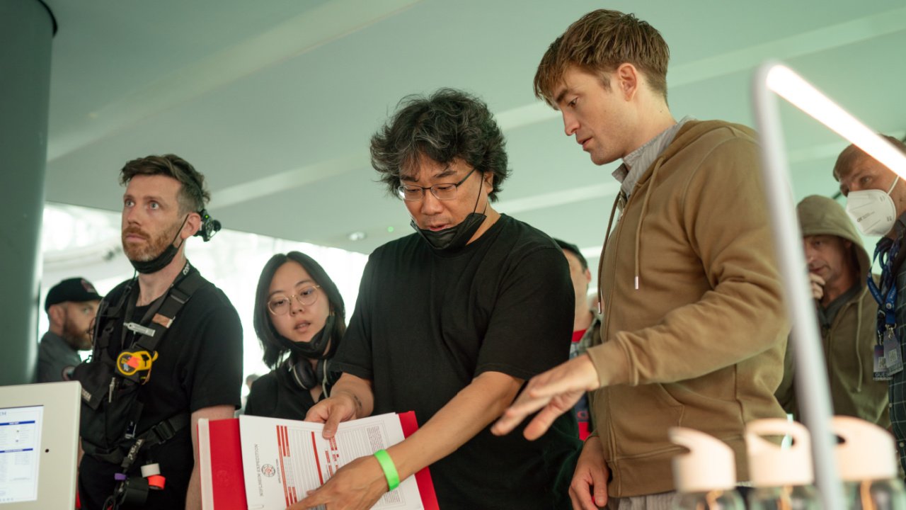 (L to r) Director Bong Joon Ho and Robert Pattinson on the set of 'Mickey 17,' a Warner Bros. Pictures release. Photo Credit: Jonathan Olley.